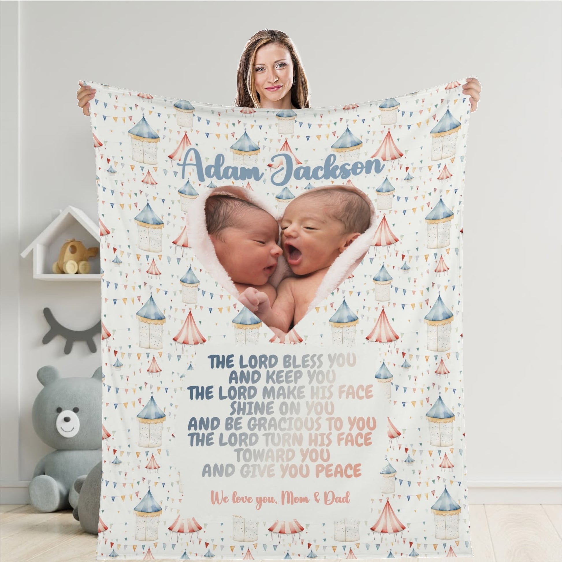 A woman holds a Personalized Baby Name Blanket, showcasing two sleeping infants. The blanket features a heart-shaped photo of the babies, adorned with circus-themed illustrations and a blessing. It includes the names "Adam Jackson" along with the words "We love you, Mom & Dad," making it an ideal personalized keepsake.