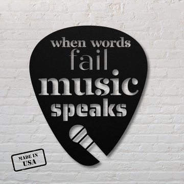 The "When Words Fail Music Speaks | Mic" sign features a black, powder-coated, guitar pick-shaped metal design with the words "when words fail music speaks" and an image of a microphone. Perfect for home decor, its "Made in USA" stamp is prominently displayed against a timeless white brick wall backdrop.