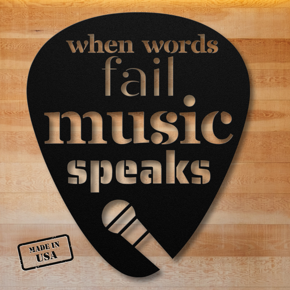 The "When Words Fail Music Speaks" sign, shaped like a black guitar pick and ideal for home decor, features the phrase intricately cut out with a microphone design at the bottom. It boasts a powder-coated finish and is proudly stamped with "Made in USA," set against a wood-textured background.