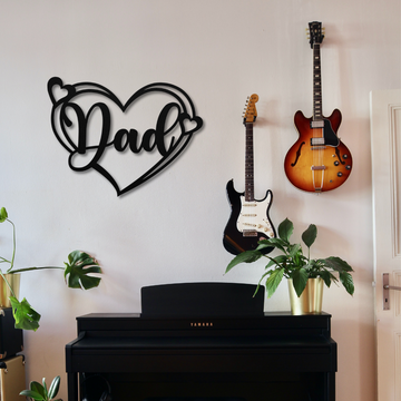 A wall featuring two guitars, the "Dad Heart Sign | Metal Wall Art," laser-cut décor, and potted plants sits above a black Yamaha piano.