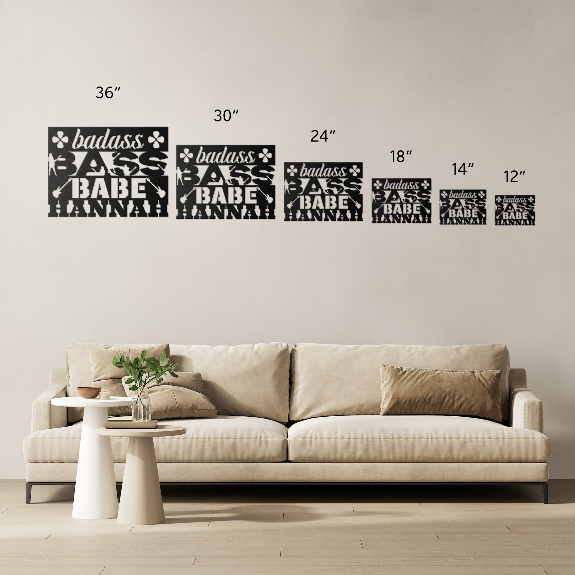A modern living room features a beige sofa and six metal wall art pieces in various sizes (12"–36"), each reading "badass BABE NANA" with florals—perfect as Badass Bass Babe custom wall art for female bass guitarists.