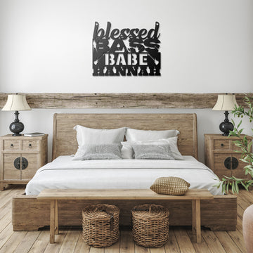 A cozy bedroom with a wooden bed, white bedding, and a bench features the “Blessed Bass Babe | CUSTOM Metal Wall Art for Female Bass Guitarist” on the wall—an ideal gift for any bass-playing woman.