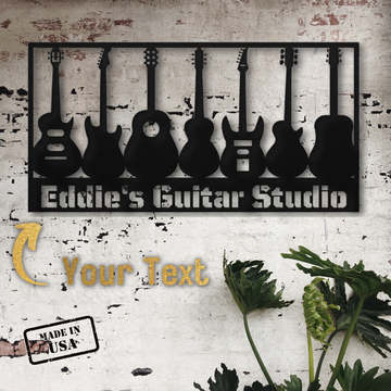 The Guitar Wall Sign Custom Name | Custom Metal Wall Art is made from 18 gauge steel with seven guitar silhouettes, "Eddie's Guitar Studio," your custom text, a "Made in USA" stamp, and green plants in the foreground.