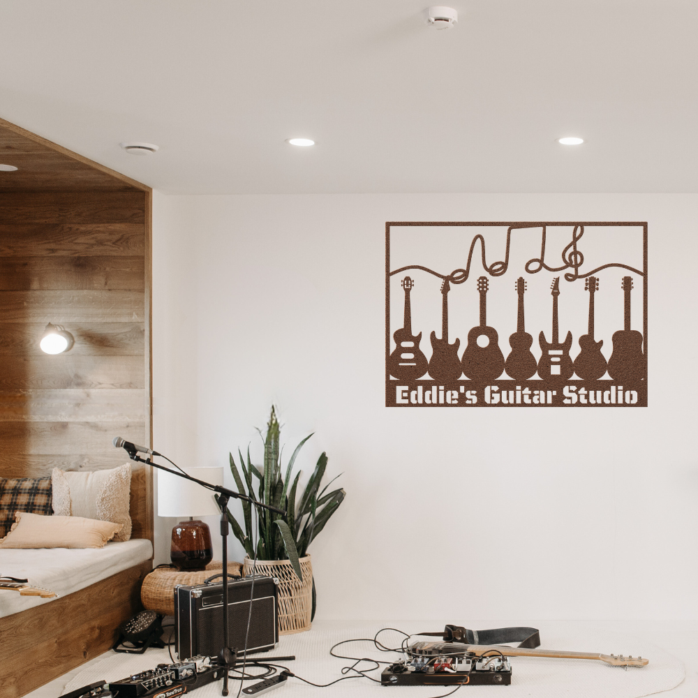 A cozy music studio features guitars on the wall, a custom metal wall art sign with music notes and personalized text, a mic stand, amps, cables, a plant, and a cushioned bench with pillows.