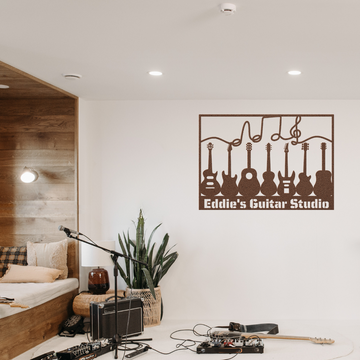 A cozy music studio features guitars on the wall, a custom metal wall art sign with music notes and personalized text, a mic stand, amps, cables, a plant, and a cushioned bench with pillows.