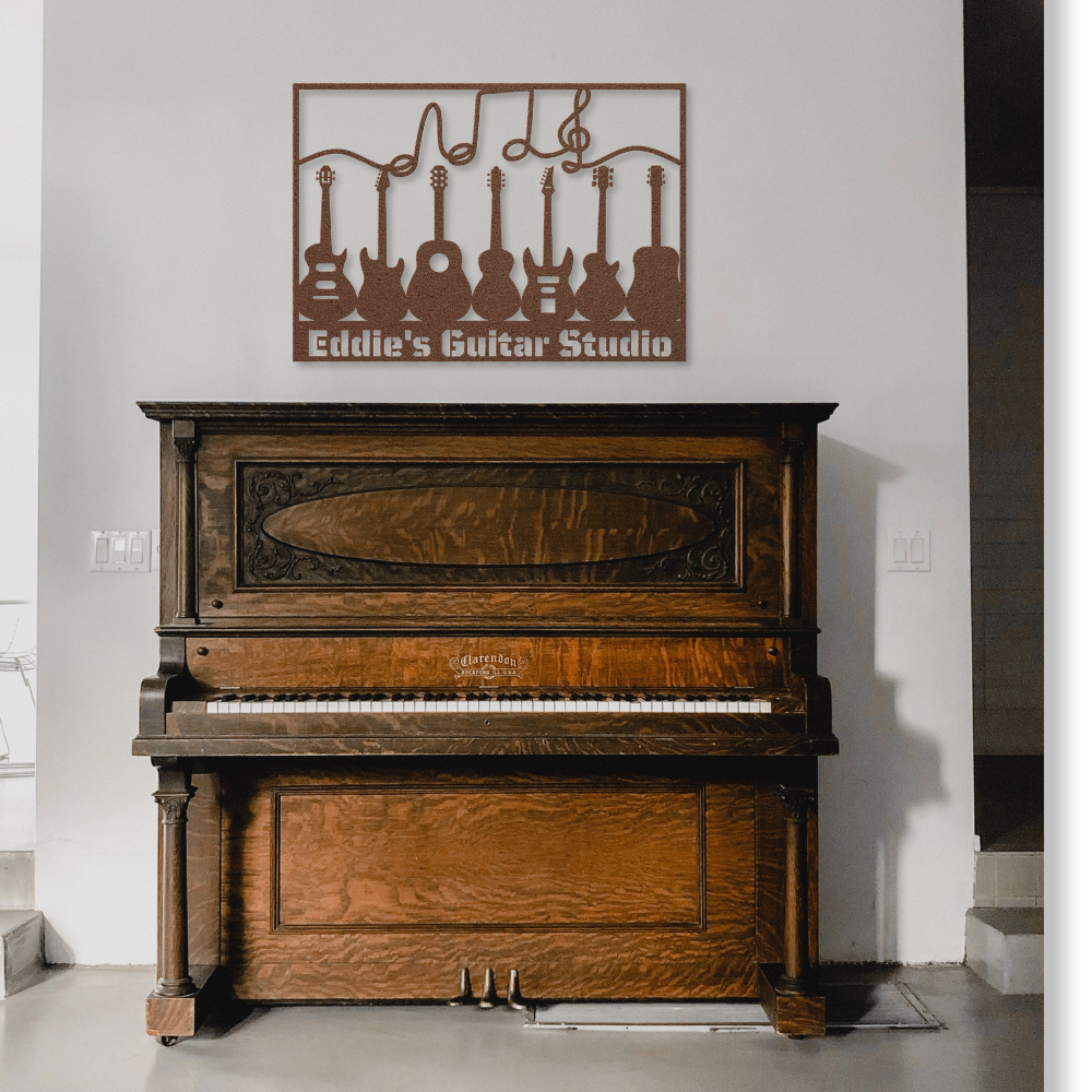 A vintage wooden piano stands against a white wall. Above it hangs the Multiple Guitars Wall Sign with Music Notes and Custom Text, a custom metal wall art featuring guitar outlines and musical notes.