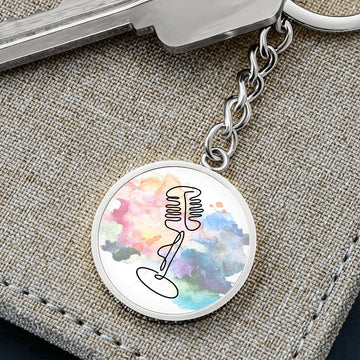 The Vintage Microphone Colorful Circle Pendant Keychain features an abstract watercolor background with a black line mic drawing, making it a perfect singer gift. It is attached to a chain with a key and displayed on textured fabric.