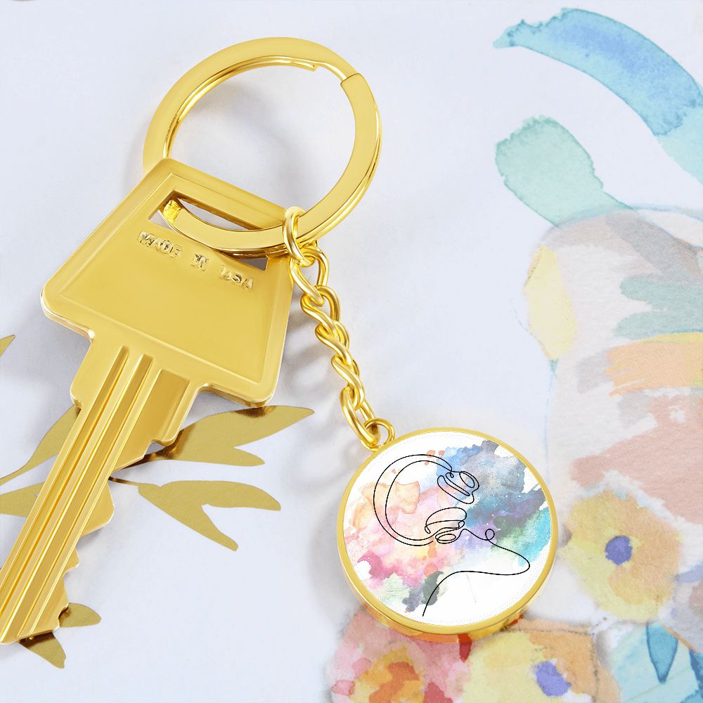 A gold key on a ring with the Head Phones Colorful Circle Pendant Keychain—featuring a vibrant, abstract design—makes an artistic, personalized gift for music lovers.