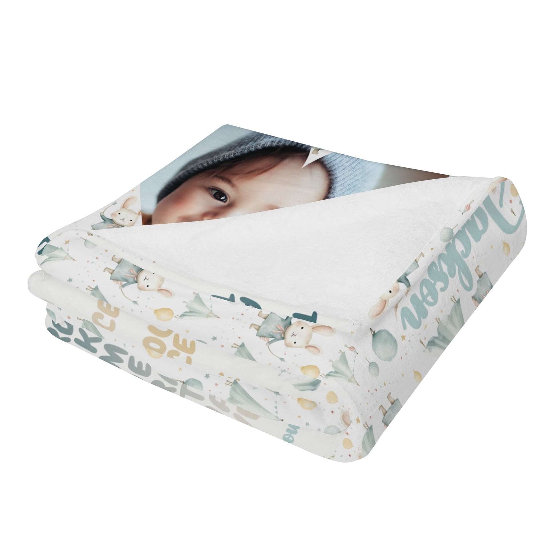 A folded blanket showcasing a partial print of a baby photo. This customized newborn name blanket is adorned with whimsical patterns, pastel-colored text, and illustrations such as trees and stars, making it an ideal personalized gift for baby blessings.