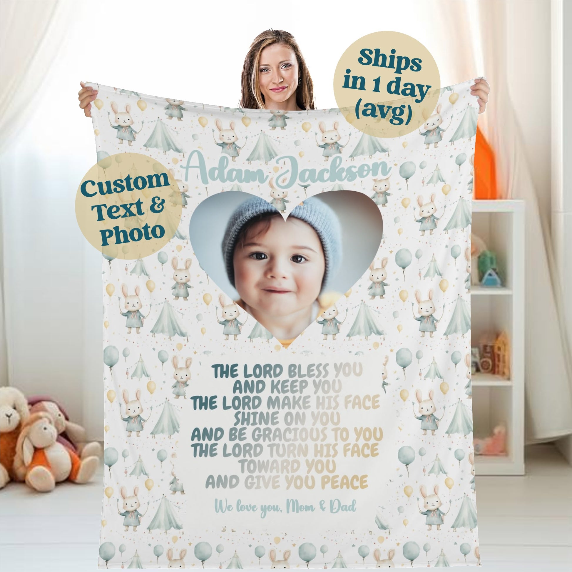 A woman holds a personalized baby name blanket that showcases a heart-shaped photo of an infant wearing a blue hat. The blanket features custom text, a sweet blessing, cartoon animals, and balloons. Ships in 1 day (avg).