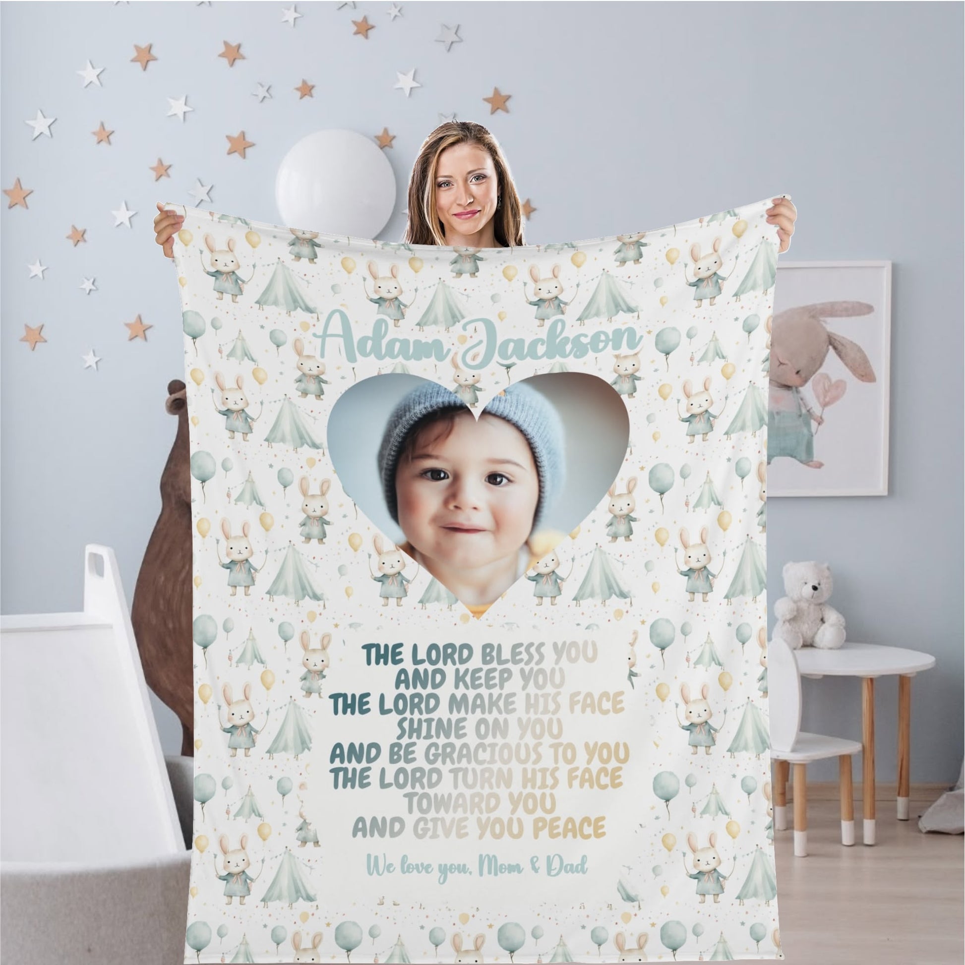 A woman holds a Personalized Baby Name Blanket, beautifully customized with a child's photo inside a heart. The adorable animal print is accompanied by the touching blessing: "The Lord bless you and keep you..." concluding with the affectionate note, "We love you, Mom & Dad." This Custom Photo Blanket Gift makes an ideal Bible verse gift for any occasion.