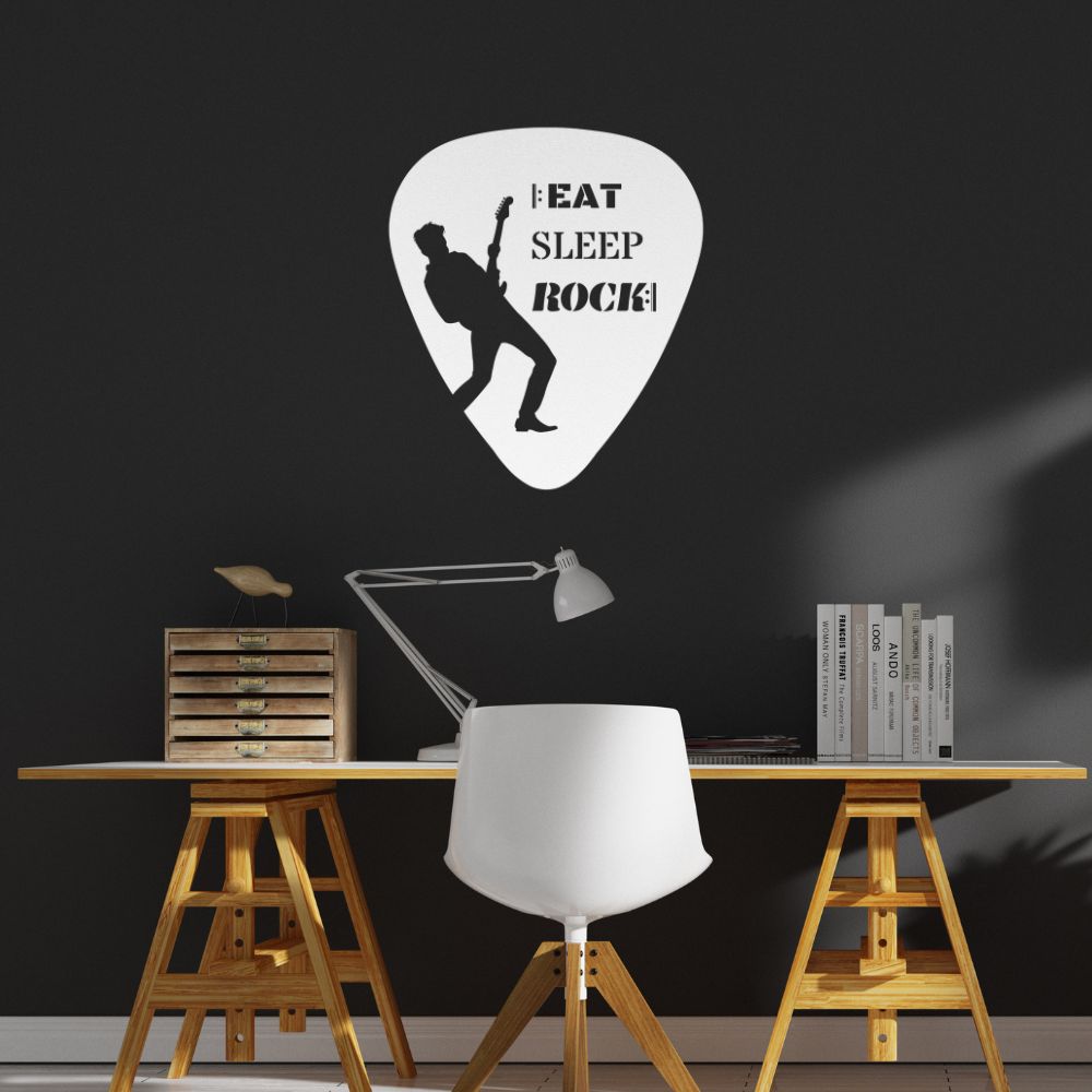 A modern workspace featuring a white chair and desk, a lamp, and wooden shelving on either side showcases the "Eat, Sleep, Rock, Repeat" guitar pick metal wall art. Made in the USA from durable powder-coated steel, this piece presents a silhouette of a guitarist with the phrase "Eat Sleep Rock!" It's ideal as a gift for guitarists and stands out against the dark wall.